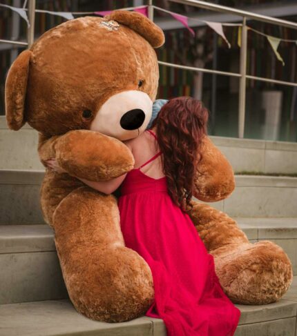 lady in red dress cuddling giant teddy bear