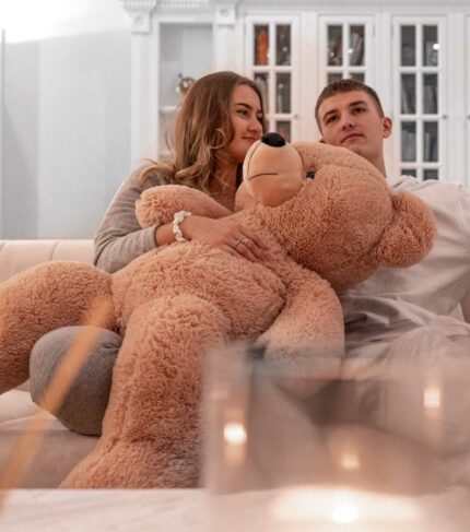 light brown teddy bear held by couple in love